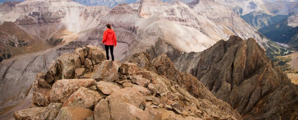 woman standing on rocky outcrop looking at mountain vista